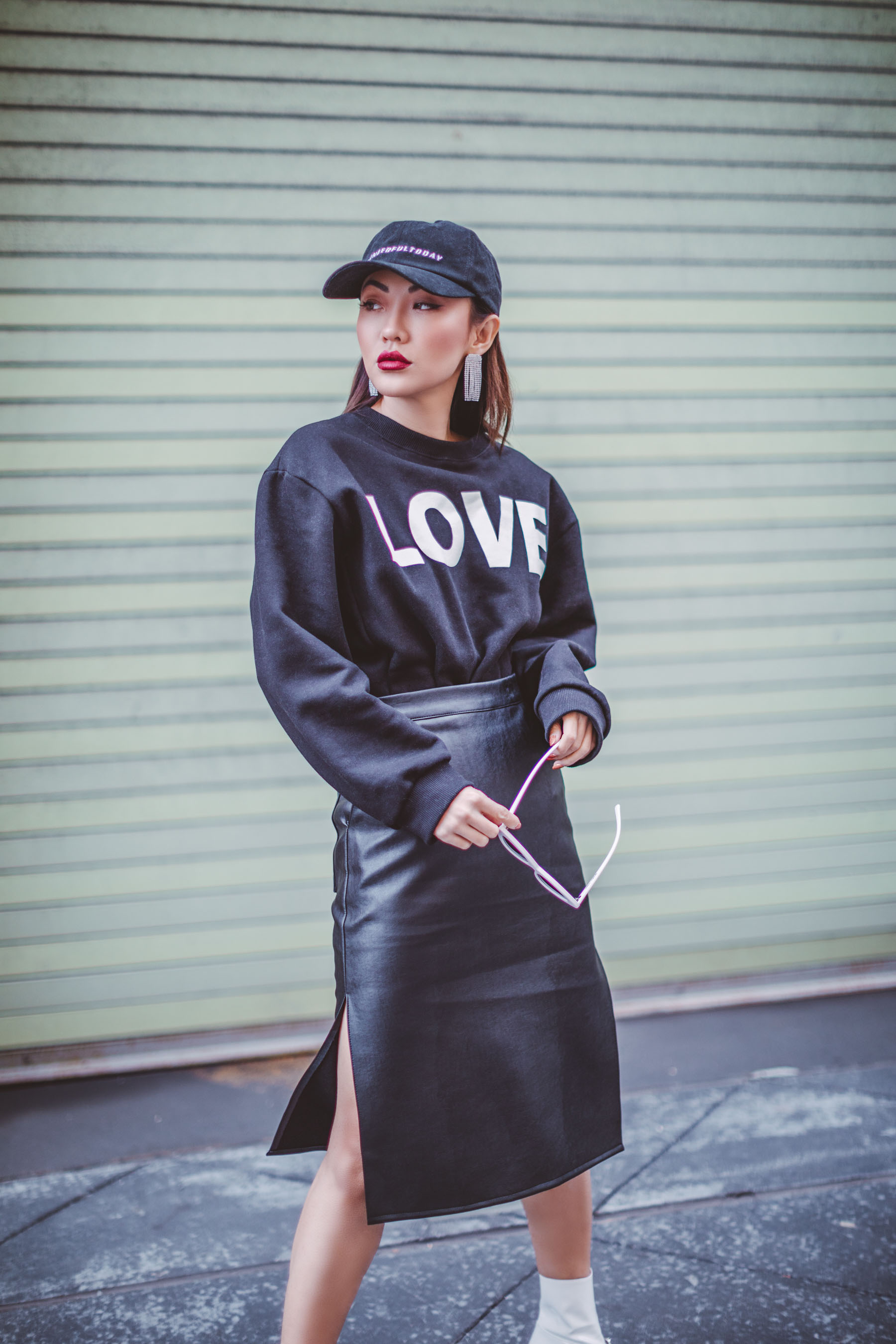 How to Look Stylish in a Quilted Puffer Jacket // Notjessfashion.com // oversized graphic sweater with baseball cap, leather skirt, and pink sunglasses, new york fashion blogger, asian blogger