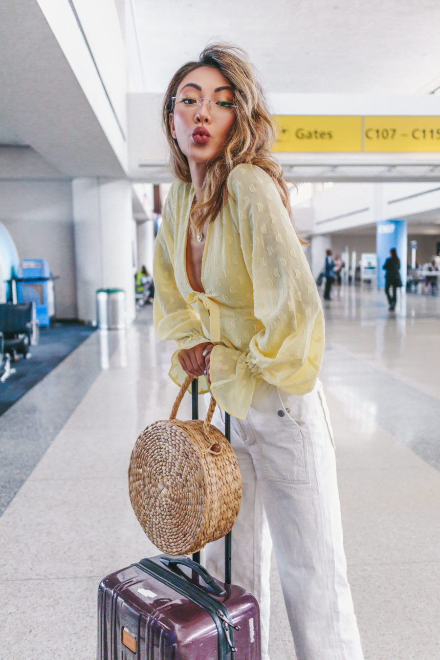 jessica wang wearing a yellow keyhole blouse with white jeans at the airport while sharing her travel essential items // Jessica Wang - Notjessfashion.com