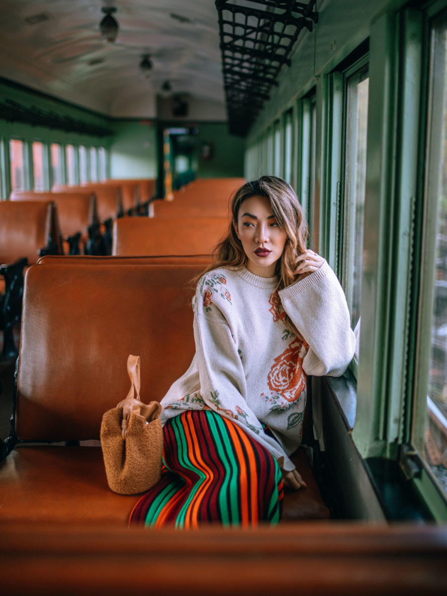 jessica wang wearing a floral print sweater and striped skirt with a faux fur bucket bag while sharing the coziest airbnb rentals in upstate new york // Jessica Wang - Notjessfashion.com