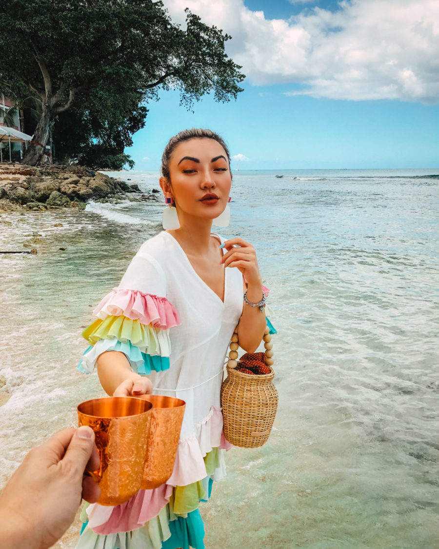 jessica wang drinking a cocktail in barbados and sharing her tropical vacation packing list